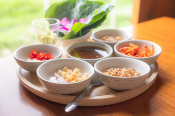 Savoury Leaf Wraps (Miang Kham) is a dish made with toasted shredded coconut, dried shrimp, fresh chili, ginger, shallots, lime, roasted peanuts and betel leaves, placed on a wooden tray.