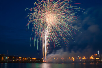 Spectacular fireworks illuminate the night sky over the water, creating a stunning display of light and color for celebrations and festive events