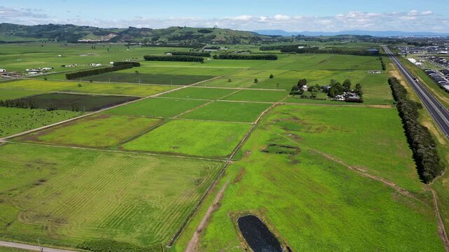 Aerial view of Papamoa countryside with bright fields, scattered farm buildings and wide open rural space. New Zealand.