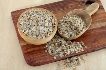Pearl millet flakes in wooden bowl and scoop
