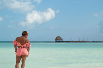 Hispanic woman enjoying tropical view with pier and palapa