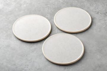 Three blank white round coasters on a textured gray surface