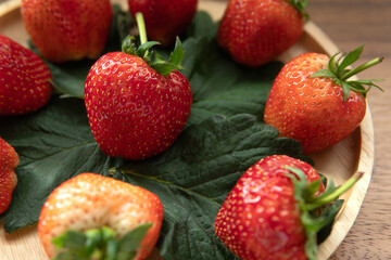 Organic fresh strawberries with leaves on bamboo wooden plate 