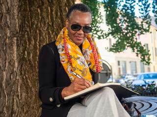 Mature woman writing journal outdoors at park