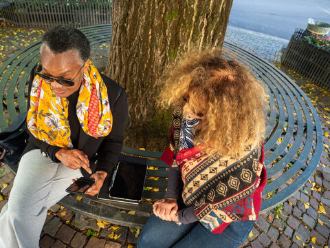 Senior women friends using smartphone digital tablet