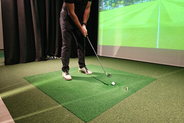 Golfer practicing swing indoors using simulation technology in training setup concept