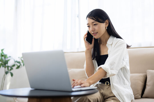 Young Woman Working from Home While Talking on Smartphone