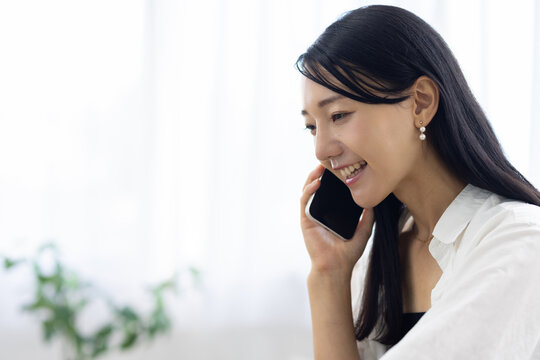 Young Woman Working from Home While Talking on Smartphone - Powered by Adobe