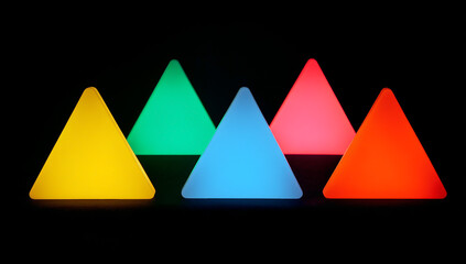Five glowing triangular light objects in various vibrant colors against black