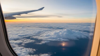 View from airplane window of lightning storm above clouds at sunset.
