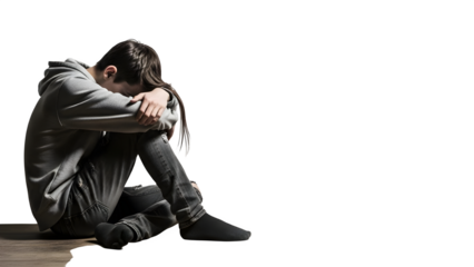 Depressed young man sitting alone on the floor with his head in his arms