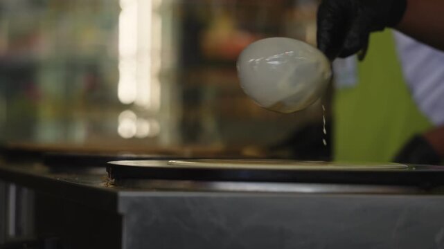 Close up view in slow motion of A Chef pouring batter to prepare a crepe in a restaurant in Paris