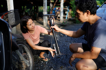 Woman and man pumping air into a motorcycle tire.