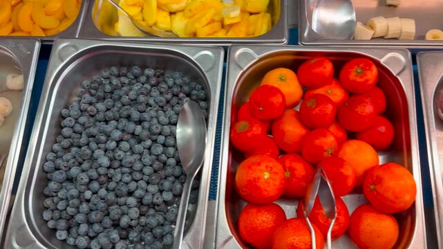 Blueberries, bananas, lychees, mandarins, chocolate pudding, peaches in the dessert buffet, tracking shot