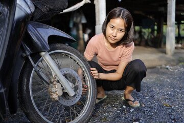 Woman pumping air into a motorcycle tire.