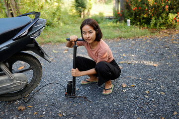 Woman pumping air into a motorcycle tire.