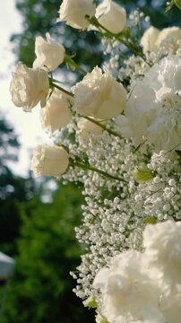 Beautiful white roses and eustoma flowers with petals and a romantic atmosphere. Outdoor wedding ceremony for the bride and groom. Decor and floristry.