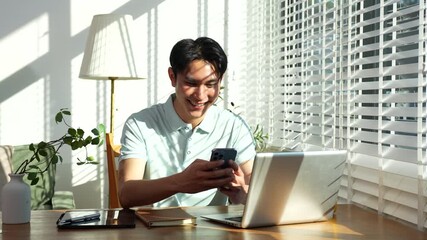 Man are using a mobile phone playing social media and laptop wifi connection, home office workplace lifestyle people. - Powered by Adobe