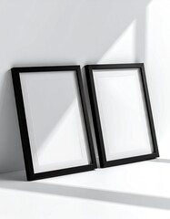 Two black framed, blank canvases on a white surface, casting shadows