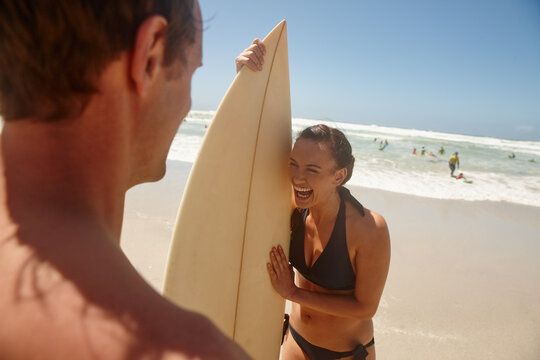 Surfboard, laughing and couple on beach for fitness, vacation or weekend trip in summer. Happy, water sports and man with woman by ocean for travel, getaway or holiday with seaside hobby together. - Powered by Adobe