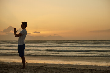 Man, meditation and yoga with sunset on beach for mindfulness, spiritual healing and zen. Person, fitness and space with namaste pose for holistic balance, inner peace and self care practice on coast