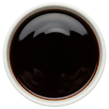 Dark brown dipping sauce in a small white ceramic bowl, viewed from above on transparent background