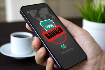 Male hands holding phone with VPN banned on screen cafe