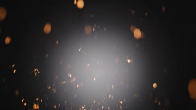 Vibrant golden-orange sparks burst brightly from a central point against a dark backdrop