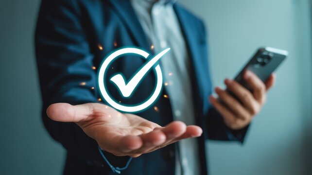 Businessman presents glowing digital confirmation symbol above open palm while holding modern communication device