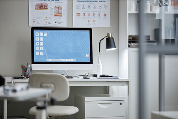 Empty dermatologist office showing modern desktop computer on desk with medical posters about skin...