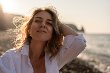 Woman, beach, sunset. Close-up portrait of a relaxed woman on a pebble beach, enjoying the golden hour light.