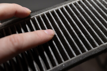 closeup finger pointing at clogged pleat and trapped dust, macro perspective reveals fiber texture