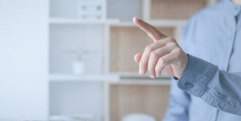  The hand of a businessman wearing a light blue shirt points straight ahead on a bright, simple white background, conveying a choice or presentation. The tone is bright, elegant.