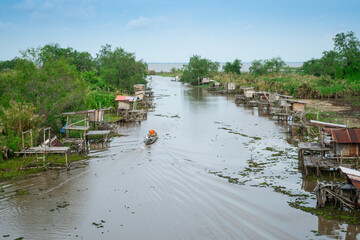 Traditional fisherman  wooden huts  of indigenous people on riverside or canal with boat at Phatthalung province ,Thailand.