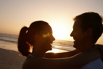 Smile, couple and hug with love at beach for travel, partner affection and holiday adventure. Happy, people and embrace with sunset for romance, tropical getaway and anniversary vacation on seashore