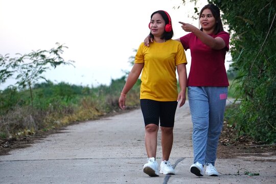 women, friends, walking, pointing, direction, companionship, outdoor, path, road, nature, exercise, fitness, leisure, conversation, bonding, guidance, exploring, yellow shirt, red shirt, movement, tog