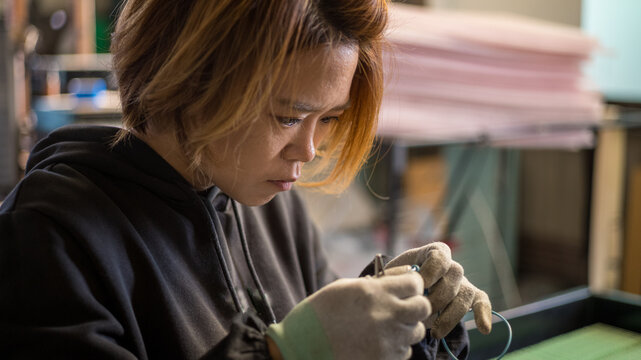 Focused factory worker performing precise manual assembly work in a manufacturing workshop
