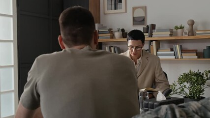 Young soldier sharing his emotions while visiting professional psychotherapist after experiencing traumatic event