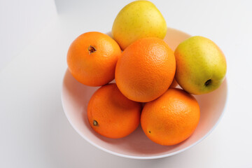 Fresh citrus fruits and green yellow seasonal apples in a white ceramic bowl