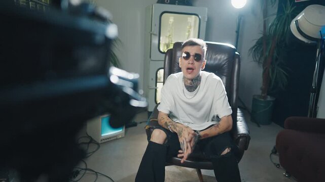 Arrogance and narcissism self-confident rap artist reading rap to camera. Portrait of handsome caucasian hip-hop singer recording musical video or content for social media, tattoos on face and body