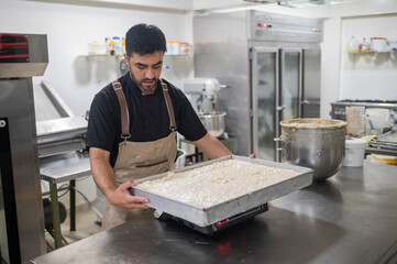 Baker weighing dough in a commercial bakery kitchen