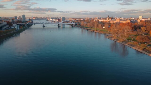 Evening Commute on Mannheim Rhine Bridge: Aerial Tracking of Heavy Traffic Entering Industrial Cityscape and Harbor District at Sunset, Germany