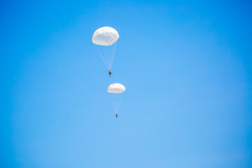 Skydiving. Flying parachutists against the background of the blue sky and mountains. Extreme sport and entertainment.