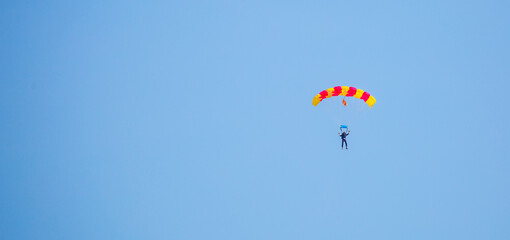 Skydiving. Flying parachutists against the background of the blue sky and mountains. Extreme sport and entertainment.