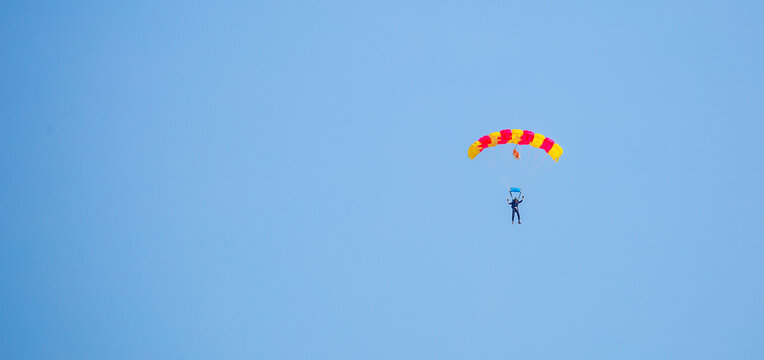 Skydiving. Flying parachutists against the background of the blue sky and mountains. Extreme sport and entertainment.