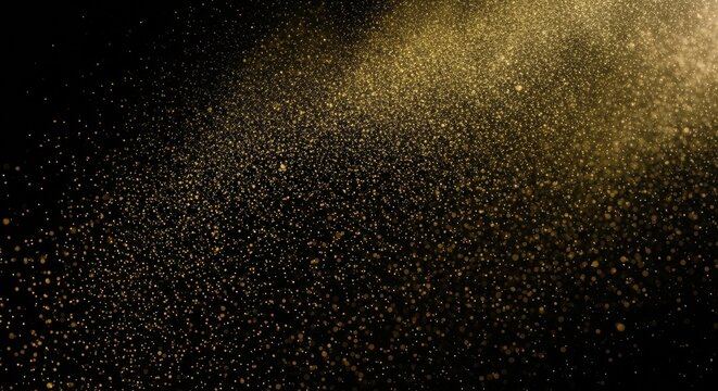 Abstract golden glitter particles sparkling brightly and falling in a magical beam of light with a beautiful bokeh effect against a solid black background for a festive design