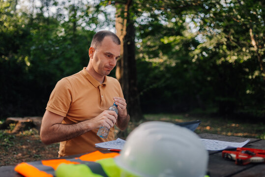 Forestry engineer opening water bottle during break in the woods - Powered by Adobe