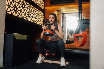 Young woman performing kettlebell squats in modern gym