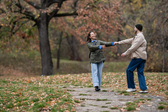 Happy couple dancing in autumn park holding hands