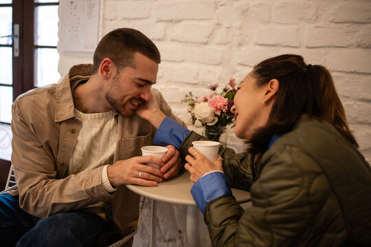 Happy young couple laughing sharing coffee on date